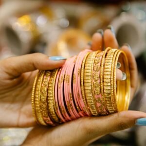 A detailed close-up of hands delicately holding ornate colorful bangles with a blurred background.