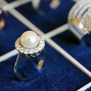 Close-up of a pearl ring with diamonds on a luxurious display.